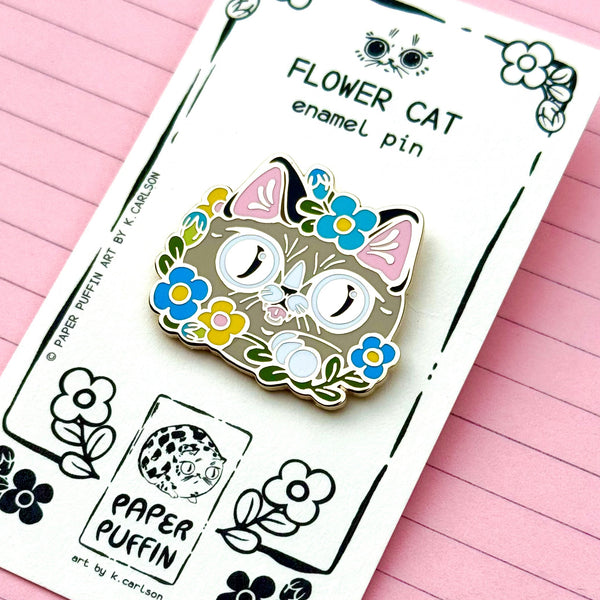 Flower cat enamel pin on a branded card with 'Paper Puffin' logo against a pink lined paper background.