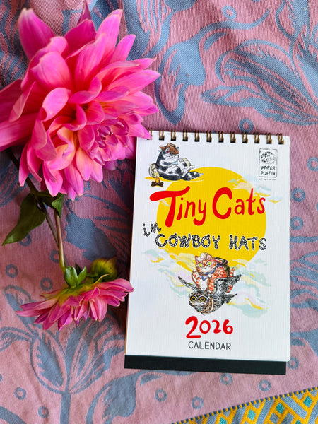 2026 calendar titled 'Tiny Cats in Cowboy Hats' with a pink flower on a patterned fabric background